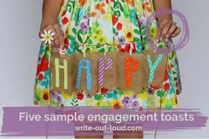 Girl wearing a colorful flowery skirt holding a piece of burlap with the word 'Happy' on it.