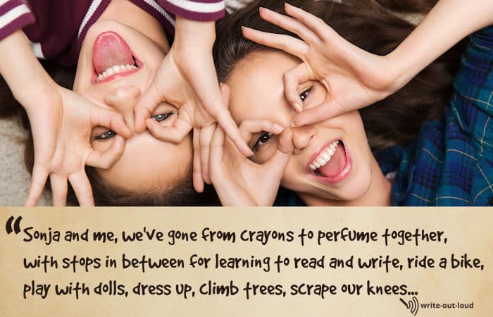 Two young girls lying on the floor making rings around their eyes with their fingers