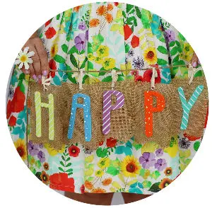 Image: flowered skirt background with woman's hands holding a string of letters spelling 'happy'.