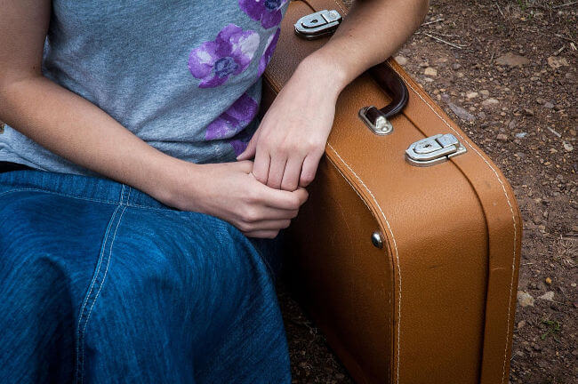 Girl resting her arm on an old-fashioned suitcase
