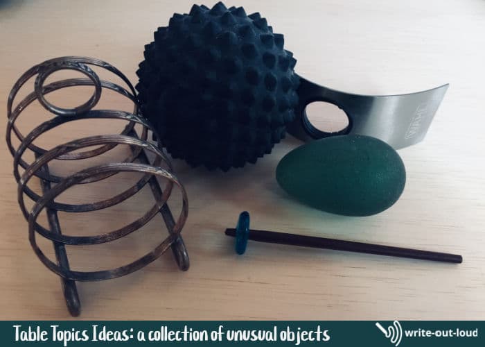 Image: small spiky black ball, old silver-plated rack, green gel egg, a piece of stainless steel, stick with bead. Text: Unusual objects for table topics.