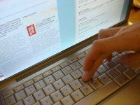 computer screen and keyboard with hand over the keys